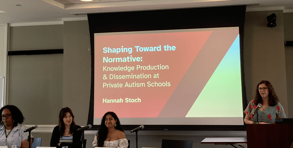 Dean Shaunté Montgomery, Zoe Florida '26, Rishika Kartik '26, seated; Hannah Stoch '26 standing at podium in front a projected slide: Shaping Toward the Normative: Knowledge Production & Dissemination at Private Autism Schools, Hannah Stoch